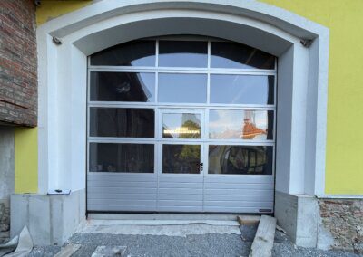 Sekční průmyslová vrata Hörmann APU42, lamela stucco, stříbrná RAL9006. Integrované dveře se sníženým prahem.